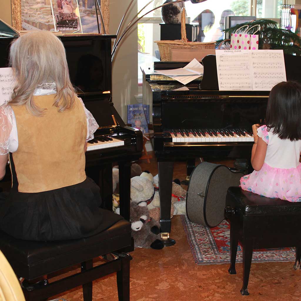 Okan Piano Academy Claudia and young female student performing duet Okan Piano Academy Claudia and young female student performing duet